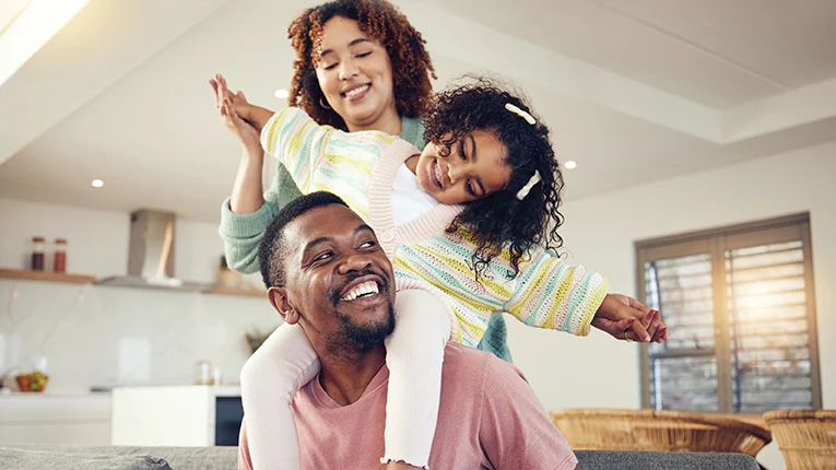 Black family, father and daughter playing with mother on living room sofa together for fun bonding at home